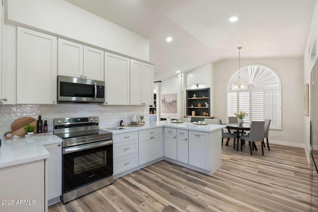 kitchen featuring light wood-type flooring, light countertops, lofted ceiling, a peninsula, and stainless steel appliances