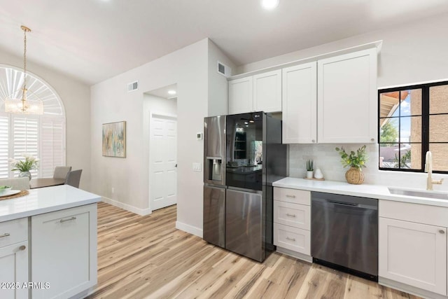 kitchen with light countertops, decorative backsplash, an inviting chandelier, stainless steel appliances, and a sink