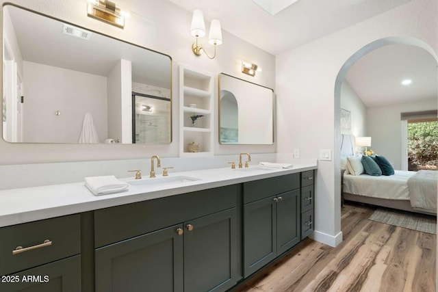 full bath featuring a sink, visible vents, wood finished floors, and double vanity