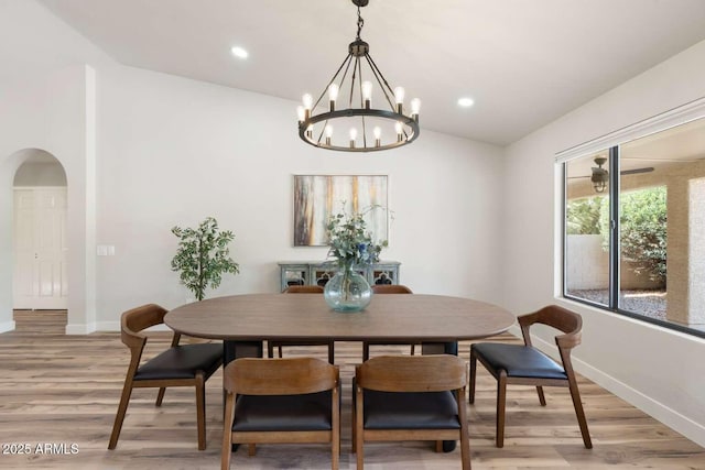 dining area featuring lofted ceiling, baseboards, arched walkways, and light wood finished floors