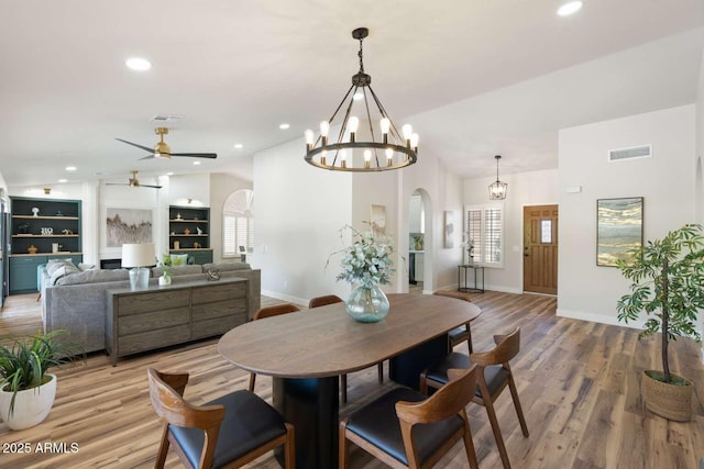 dining room with visible vents, light wood-style flooring, recessed lighting, arched walkways, and vaulted ceiling