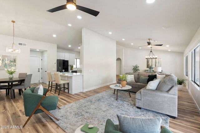 living room with lofted ceiling, a healthy amount of sunlight, visible vents, and arched walkways