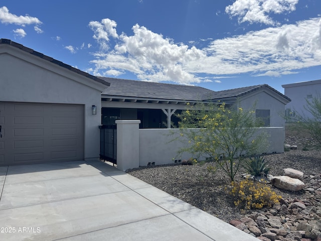 single story home featuring concrete driveway, a tiled roof, an attached garage, stucco siding, and a fenced front yard