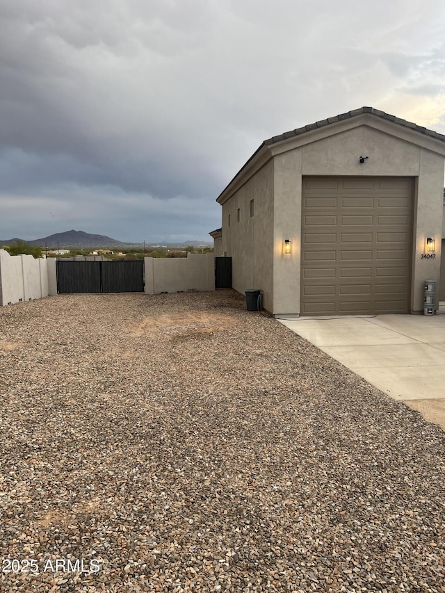 view of property exterior with driveway, stucco siding, and fence