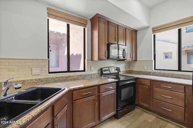 kitchen featuring tasteful backsplash, light wood-type flooring, a sink, and black appliances