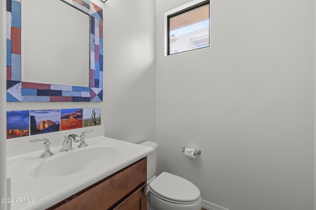 half bath with toilet, a textured wall, and vanity