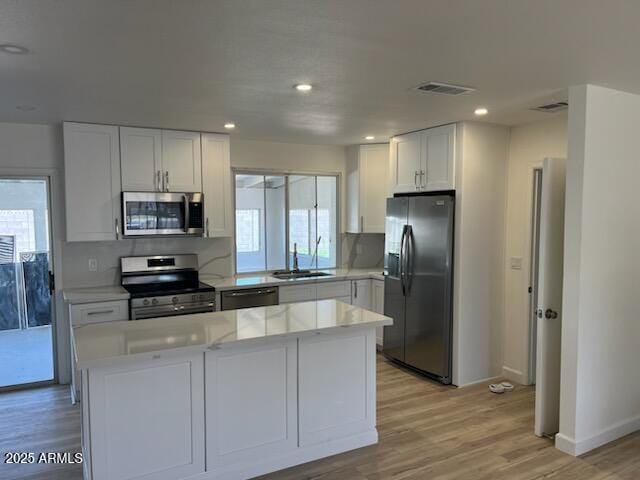 18045 N 20th Ln N, Phoenix, AZ 85023 - kitchen featuring stainless steel appliances, light wood-type flooring, backsplash, white cabinetry, and a center island