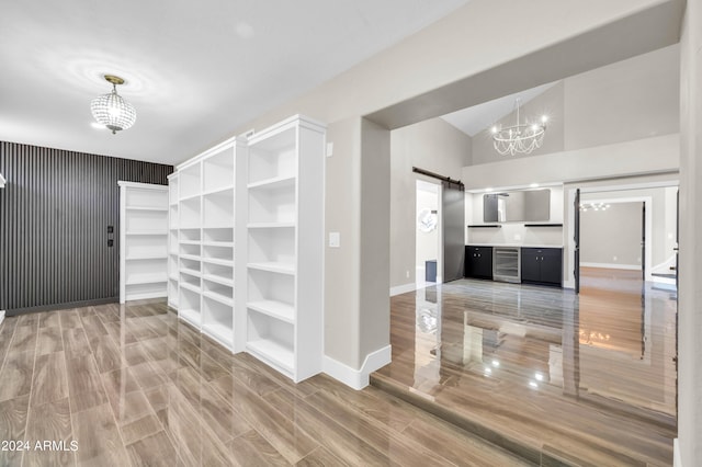 spacious closet featuring a barn door, wood-type flooring, beverage cooler, and an inviting chandelier