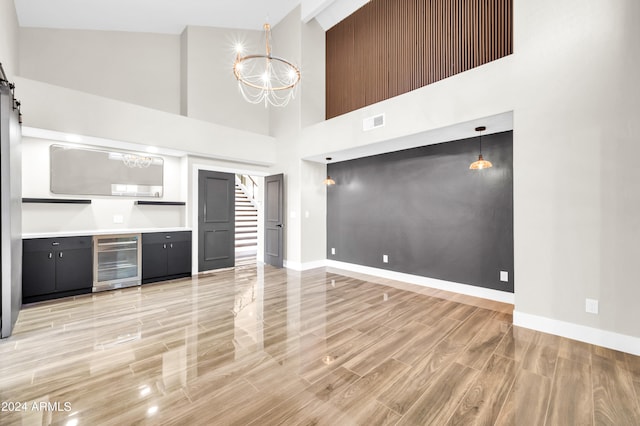 kitchen with high vaulted ceiling, a notable chandelier, decorative light fixtures, and wine cooler