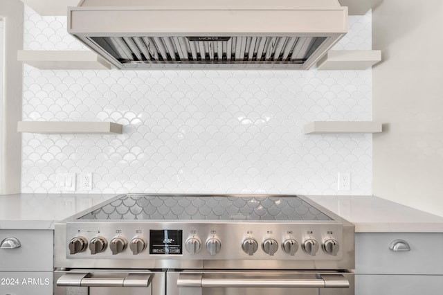 room details with decorative backsplash, high end stainless steel range oven, and exhaust hood