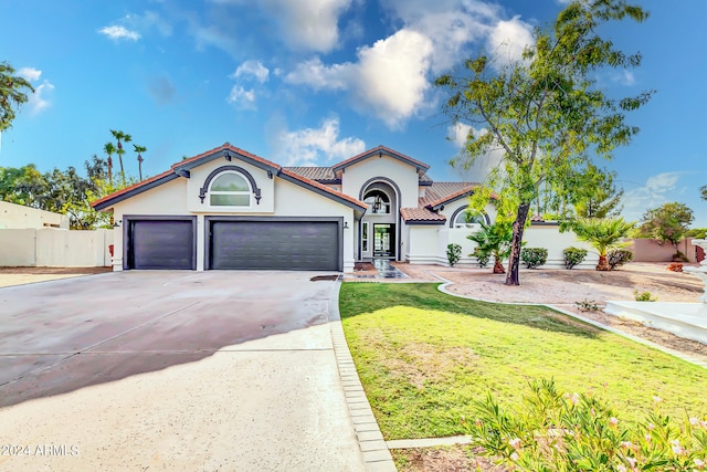 mediterranean / spanish-style home with a front yard and a garage