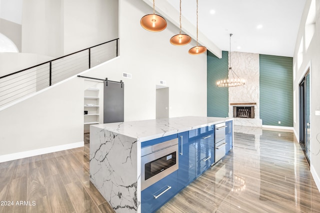 kitchen featuring a barn door, a spacious island, pendant lighting, and light stone counters