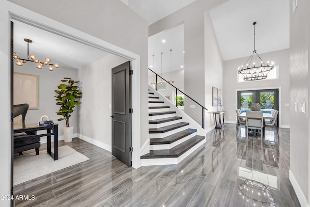 entryway with a chandelier, french doors, high vaulted ceiling, and wood-type flooring