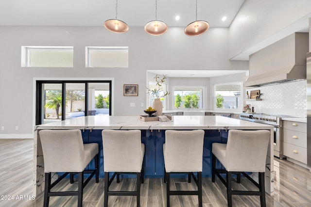 kitchen featuring custom range hood, decorative light fixtures, stainless steel range oven, a high ceiling, and a center island