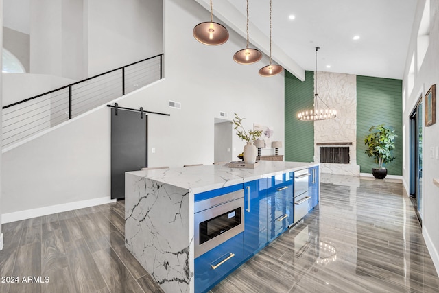 kitchen featuring pendant lighting, a barn door, a spacious island, and light stone counters