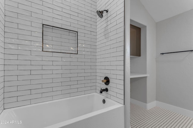 bathroom with tile patterned flooring, tiled shower / bath, and lofted ceiling