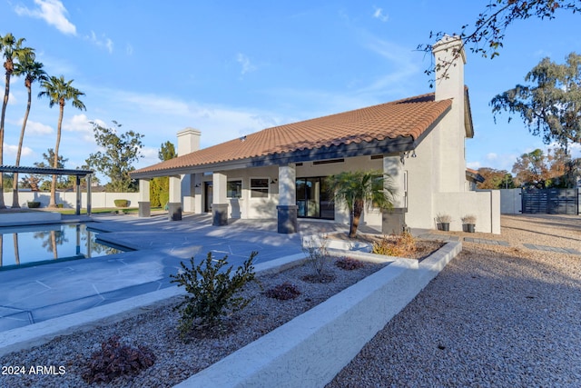 rear view of property featuring a patio area, a fenced in pool, and a pergola