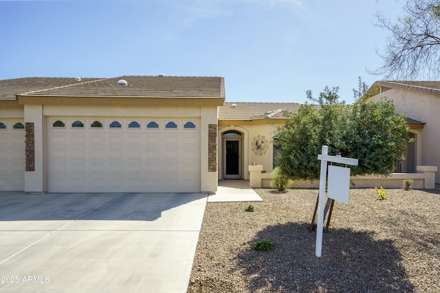 view of front of property with an attached garage, driveway, a tile roof, and stucco siding