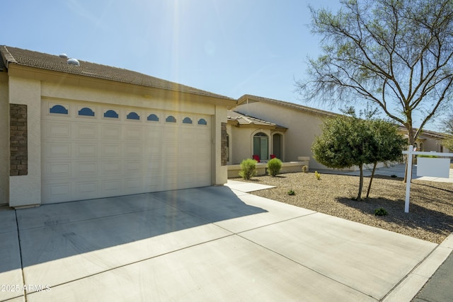 view of front of home with an attached garage, concrete driveway, and stucco siding