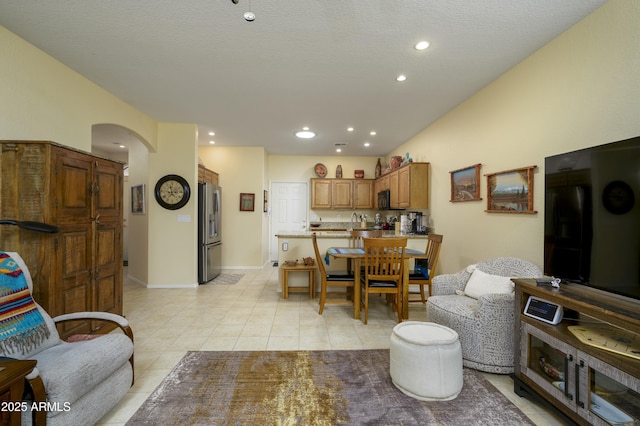 living room featuring light tile patterned floors, baseboards, arched walkways, and recessed lighting