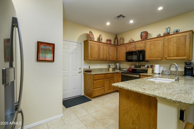 kitchen featuring light stone counters, electric range, a sink, black microwave, and a peninsula