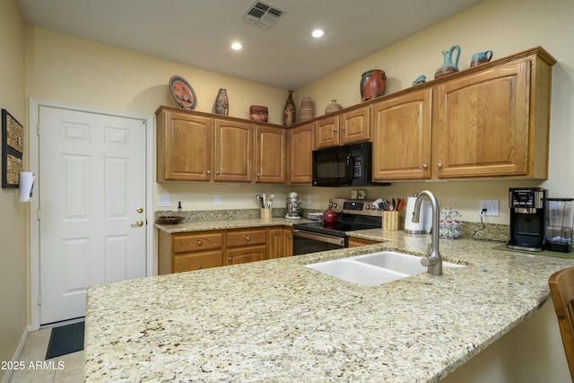 kitchen featuring visible vents, a peninsula, stainless steel electric range, black microwave, and a sink