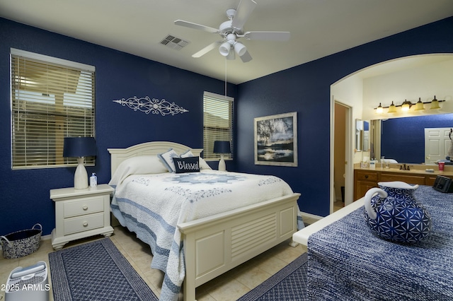 bedroom featuring visible vents, arched walkways, baseboards, ceiling fan, and light tile patterned flooring