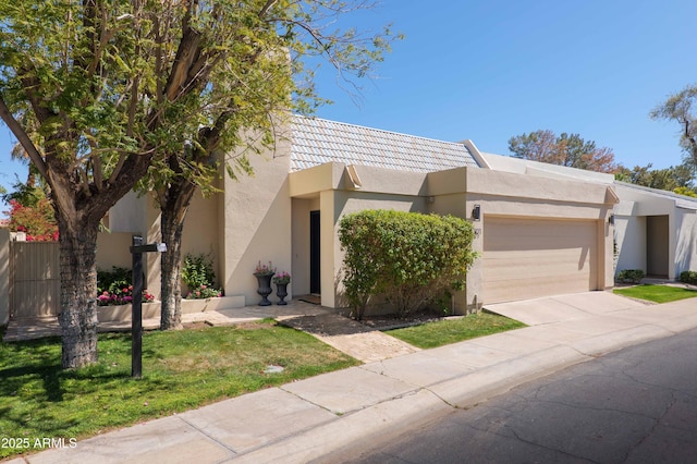 view of front facade featuring driveway, a tile roof, stucco siding, fence, and a garage