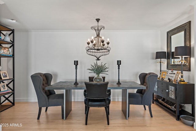 dining room featuring ornamental molding, baseboards, light wood-style floors, and a chandelier