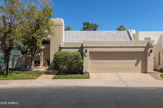 view of front of house featuring fence, stucco siding, a garage, and concrete driveway