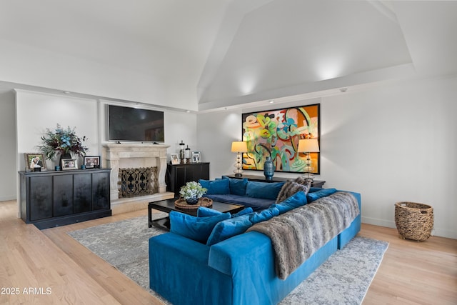 living room with baseboards, a fireplace, high vaulted ceiling, and wood finished floors