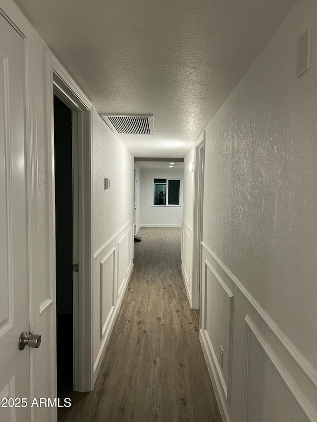 corridor featuring wood-type flooring and a textured ceiling