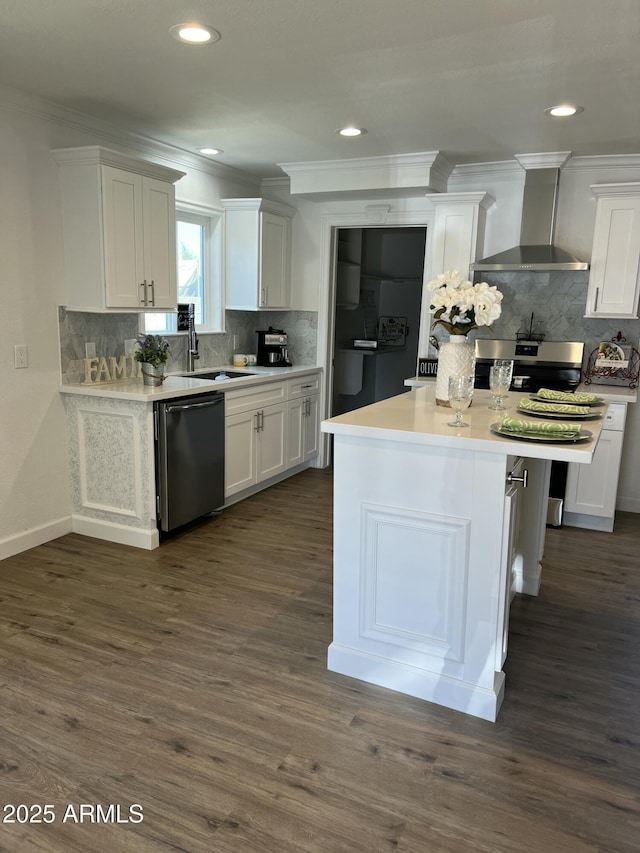 kitchen featuring wall chimney exhaust hood, white cabinetry, crown molding, a center island, and appliances with stainless steel finishes