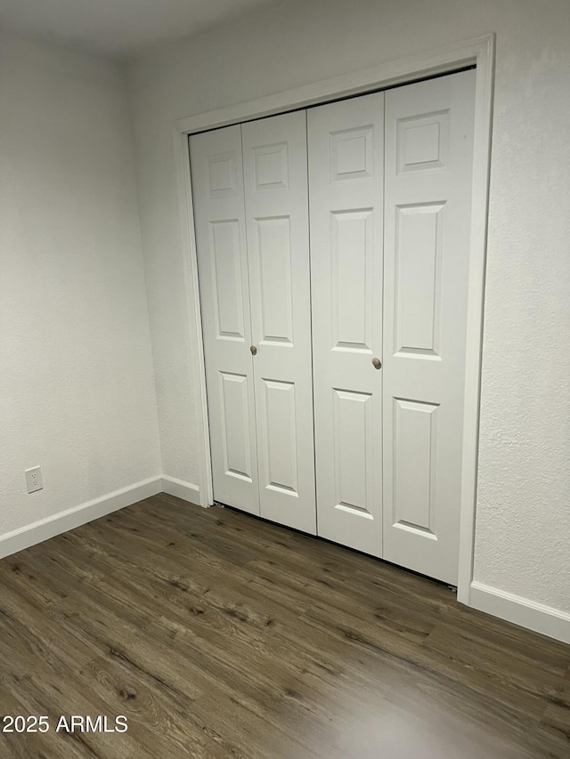 unfurnished bedroom with dark wood-type flooring and a closet