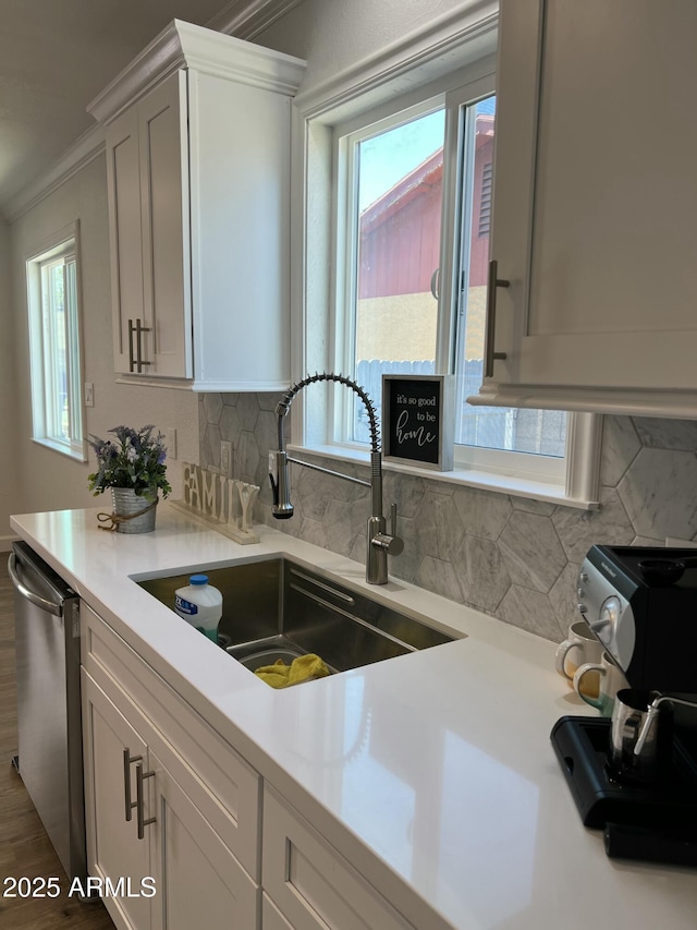 kitchen featuring white cabinets, dishwasher, sink, and backsplash