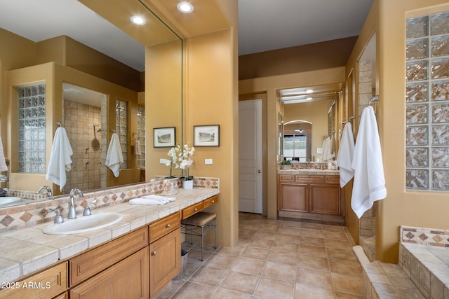 bathroom featuring tile patterned flooring, tiled shower, recessed lighting, and vanity