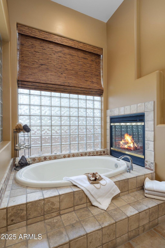 full bath with a garden tub and a tile fireplace