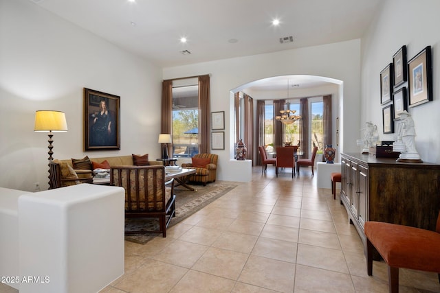 living area featuring visible vents, light tile patterned flooring, recessed lighting, arched walkways, and a notable chandelier