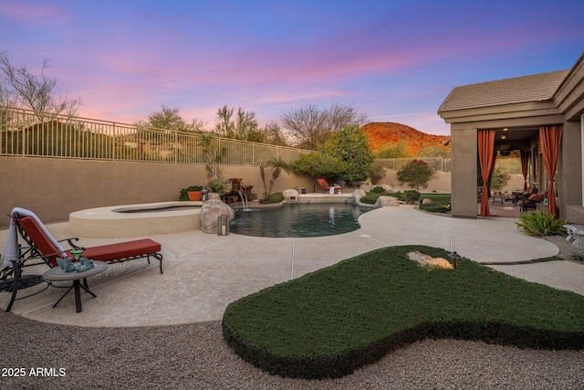 pool at dusk with a patio, a fenced in pool, an in ground hot tub, a fenced backyard, and a mountain view