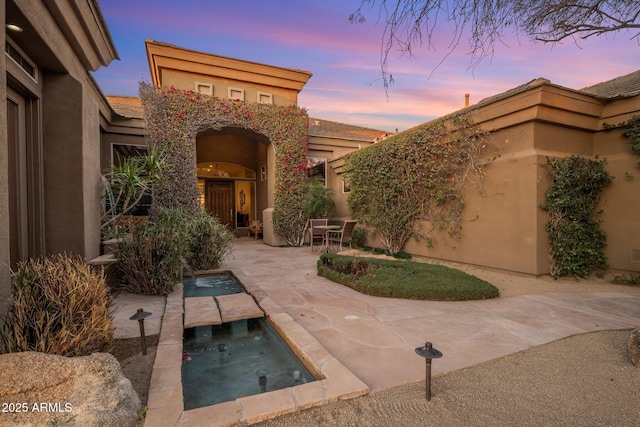 patio terrace at dusk featuring an outdoor pool