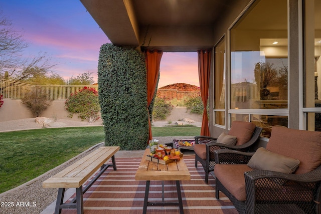 patio terrace at dusk with a fenced backyard, a lawn, and an outdoor hangout area