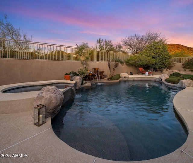 pool at dusk featuring a fenced in pool, an in ground hot tub, and fence
