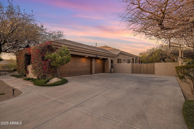 view of front of property featuring stucco siding, a gate, fence, concrete driveway, and an attached garage