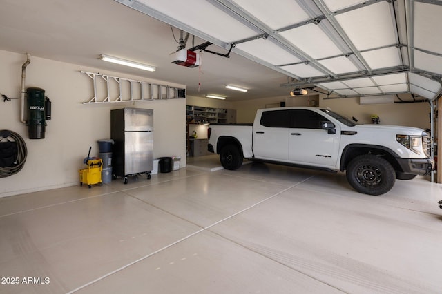 garage featuring a garage door opener and freestanding refrigerator