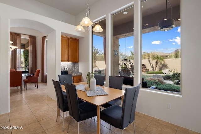 dining area featuring arched walkways, plenty of natural light, and light tile patterned flooring