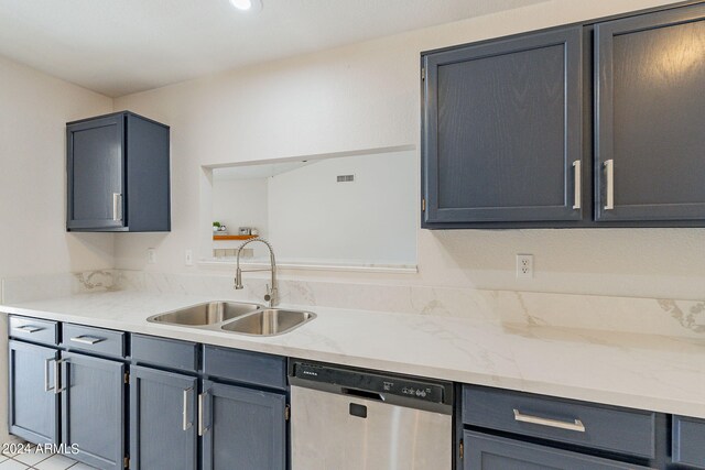 kitchen featuring light tile patterned floors, sink, stainless steel dishwasher, and light stone counters