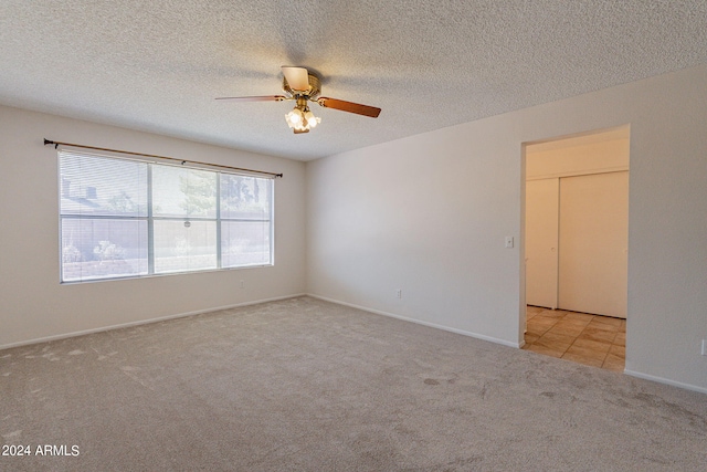 carpeted spare room featuring ceiling fan and a textured ceiling