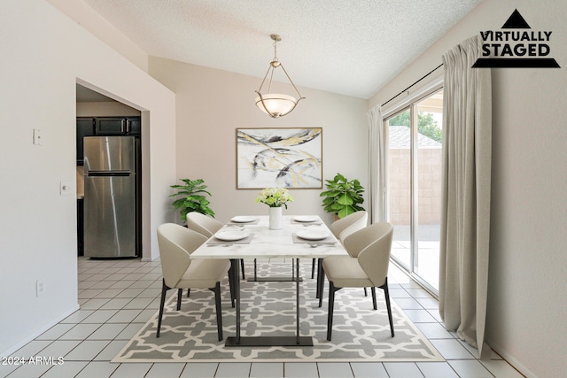 dining area featuring lofted ceiling, light tile patterned floors, and a textured ceiling