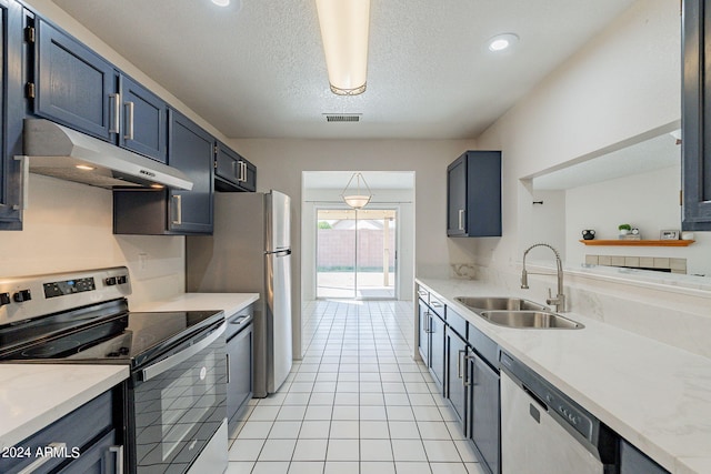 kitchen with a textured ceiling, stainless steel appliances, sink, and light tile patterned flooring