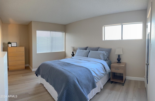 bedroom with a textured ceiling and light wood-type flooring